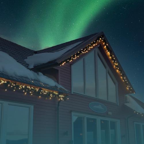 Julebord på Arnøy Brygge. Arnøy Brygge med snø på taket og nordlys på himmelen over. 